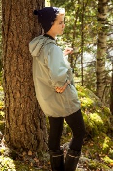 Female tourist leaning on tree in wood scenic photography. Picture of person with woodland on background. High quality wallpaper. Photo concept for ads, travel blog, magazine, article. Female tourist leaning on tree in wood scenic photography