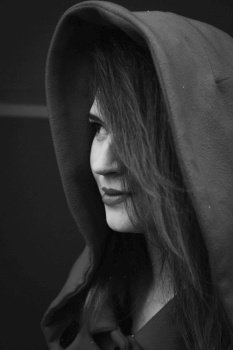 Close up pretty young woman wearing coat with hood monochrome portrait picture. Closeup side view photography with grey background. High quality photo for ads, travel blog, magazine, article. Close up pretty young woman wearing coat with hood monochrome portrait picture