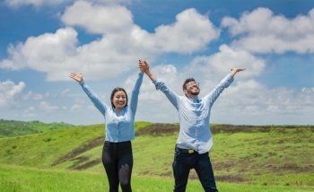 Concept of a happy and free couple in the field, Couple on the hill with hands raised to the sky, Happy couple in the field raising hands to the sky