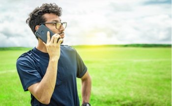Man calling by cell phone, young man in the field calling by cell phone