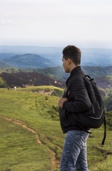 closeup of a backpacker watching a hill, adventurous man watching a hill with background horses on the hill, man with backpack on a hill