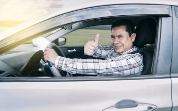 Portrait of a man showing thumbs up while driving, Man in his car giving a thumbs up, happy man in his car giving a thumbs up