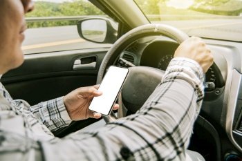Man using his phone while driving, Person holding the cell phone and with the other hand the steering wheel, Concept of irresponsible driving, Distracted driver using the cell phone while driving