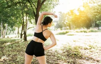 Athlete girl stretching arms before running. Concept of physical activity and healthy life, Athlete girl doing warm-up exercises in a park, Sporty woman doing stretching exercises before running