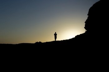 Image of the silhouette of a man on a rock with the sun backlit, silhouette of a person on a rock, entrepreneurship concept