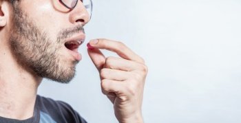 Man putting a pill in his mouth isolated. Close-up of a man taking an aspirin. Person taking a pill isolated, Close up of young man putting a pill in his mouth. Self-medication concept