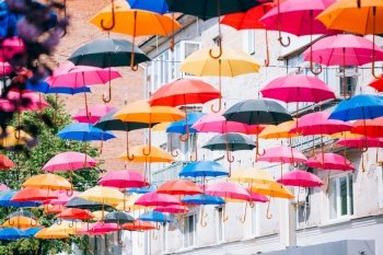 Colorful umbrellas hanging over the old streets of the city. The street is decorated with colored umbrellas. Umbrella street decoration Sky of colorful umbrellas.