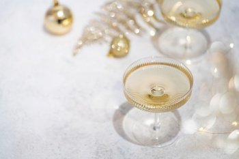 Two champagne glasses on gold shiny background with glitters and balls, top view. Two champagne glasses