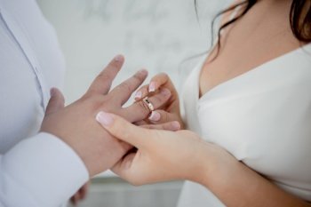 a bride and groom exchange wedding rings on their hands. the bride and groom exchange wedding rings on their hands