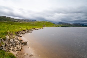 A landscape view of Loch Assynt with the ruins of the Calda House in the background