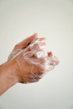 close up of female hands with soapy suds on a white background