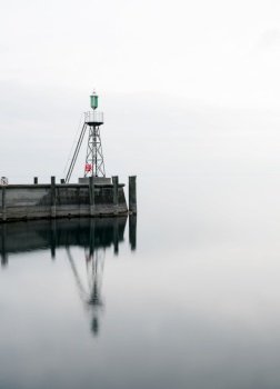 The harbor jetty at Rorschach harbor on a typical April spring morning on Lake Constance in Switzerland. Long exposure with lots of negative space.