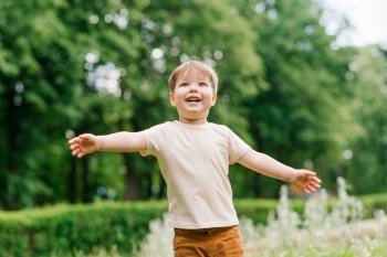 Emotional portrait of a three-year-old boy having fun in a summer park