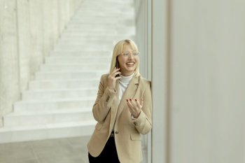 Businesswoman using mobile phone while standing on the modern office hallway