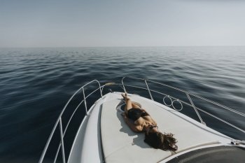 View at young attractive woman relaxing on luxury yacht floating on ablue sea