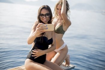 Two pretty young women taking selfie on vacation at the yacht in summer