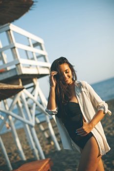 View at young woman posing on the beach by lifeguard observation tower