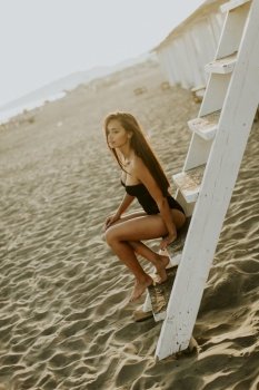 View at young woman posing on the beach by lifeguard observation tower