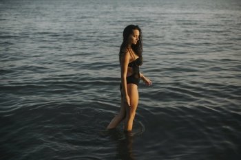 Pretty young woman walking in water at the beach