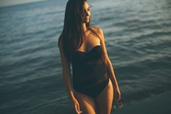 Pretty young woman in the sea on a sunnset of a summer day