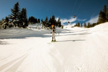 A single girl enjoys a sunny winter day of skiing, dressed in full snow gear with ski boots and sunglasses