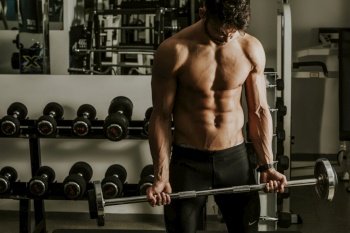Portrait of strong and handsome young man doing exercise with dumbbells