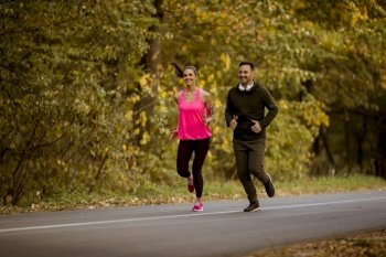 Young couple jogging together in autumn park