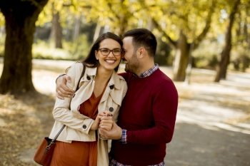 Loving young woman and man walking in city park holding hands