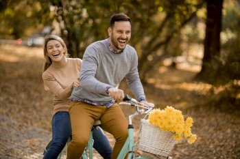 Active young couple enjoying together in riding bicycle at golden autumn park
