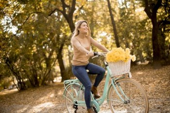 Happy active woman riding bicycle in golden autumn park