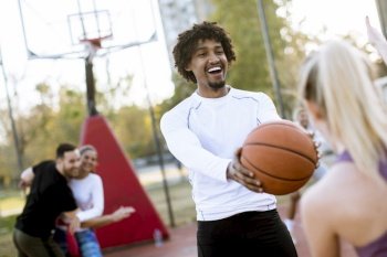 Multiracial couple playing basketball on outdoor court at outumn day