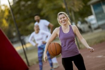 Portrait of fitness young woman with basketball ball playing game outdoor