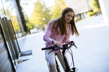 Pretty young woman riding an electric bicycle in urban environment