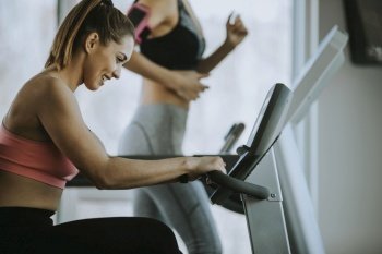 Pretty young woman using treadmill in modern gym