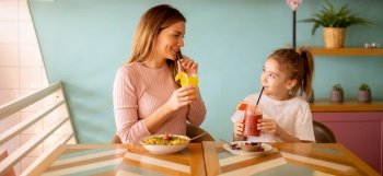 Mother and daughter having good time during breakfast with fresh squeezed juices in the cafe