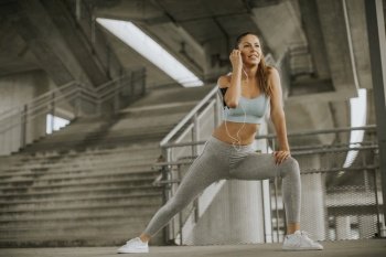 Pretty young woman with armband having exercise in the urban environment