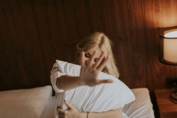 Portrait of happy blonde woman hugging her pillow at home in the bedroom