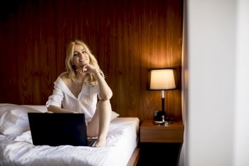 Portrait of a smiling casual young woman using laptop in bed at home