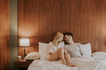 Young adult heterosexual couple on bed in bedroom at home
