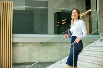 Cute young business woman walking on stairs in the office hallway