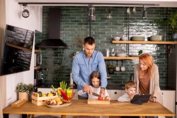 Happy young family preparing vegetables in the kitchen