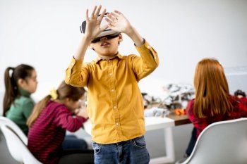 Cute little boy wearing VR virtual reality glasses in a robotics classroom