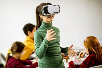 Cute little girl wearing VR virtual reality glasses in a robotics classroom