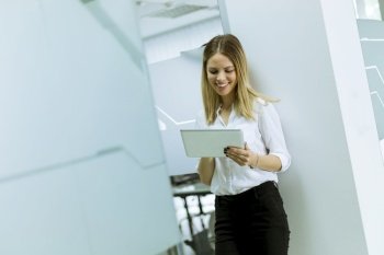 Portrait of young businesswoman standing with tablet in office