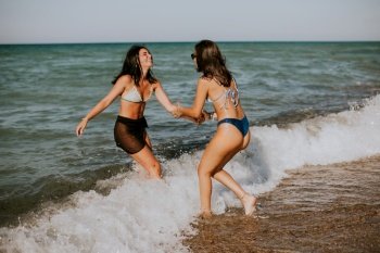 Two pretty young woman having fun on the seaside at hot summer day
