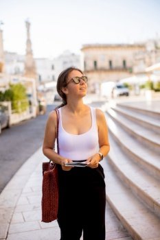 Female tourist with a city map by the Saint Oronzo statue in Ostuni, Italy