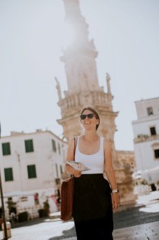 Female tourist with a city map by the Saint Oronzo statue in Ostuni, Italy