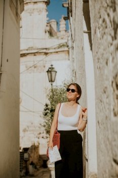 Female tourist with a paper city map on narrow streets of Ostuni, Italy