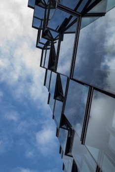 Facade of a skyscraper building with a glassy view of the sky and reflection in the windows