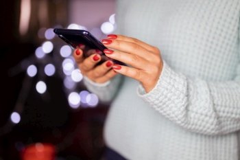 girl holding a modern smartphone in her hands online against a background of bokeh for the new year